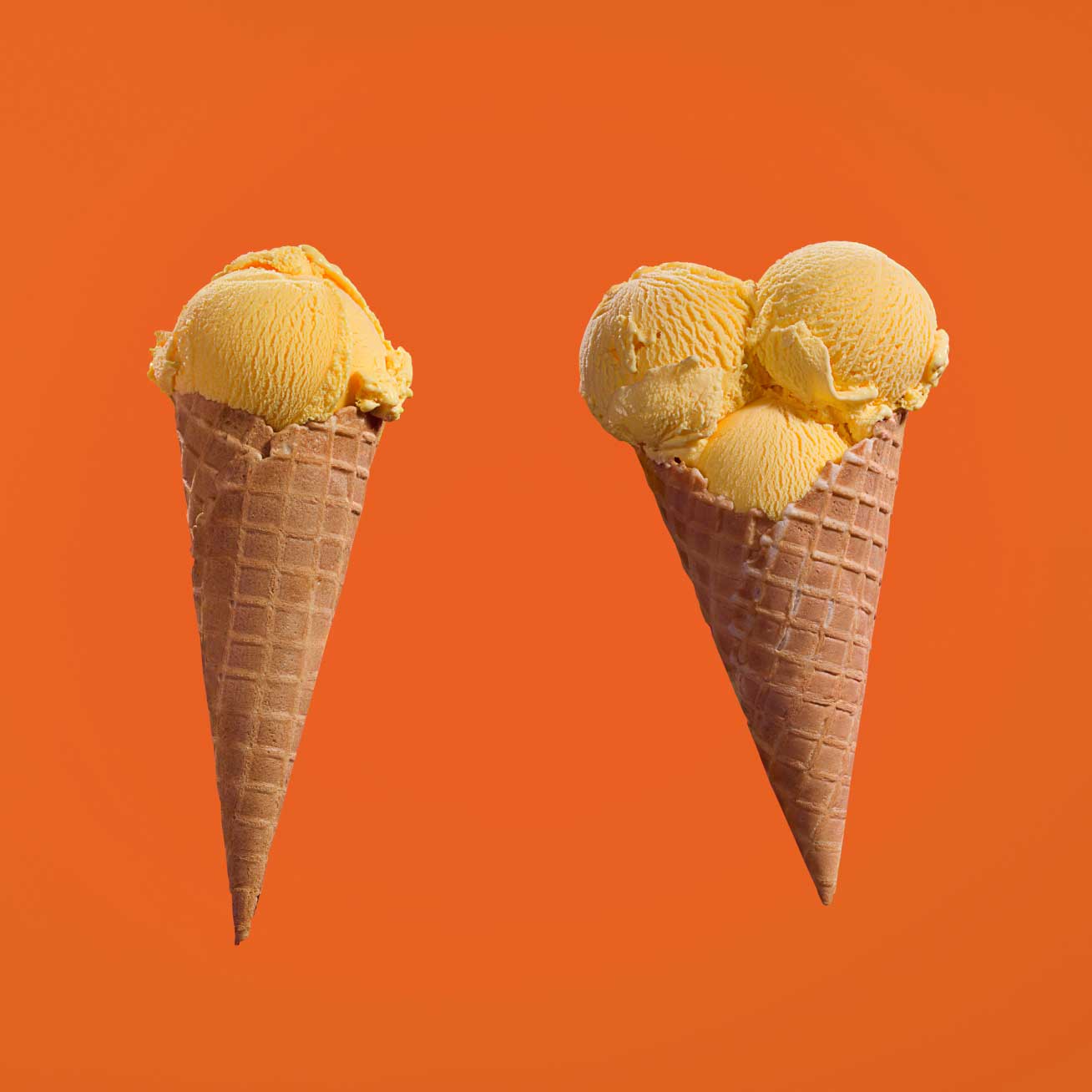 Two ice cream cones on an orange background
